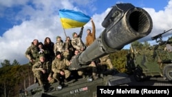 Украинские военнослужащие позируют с флагом на танке Challenger 2 во время учений в лагере Бовингтон недалеко от Вула на юго-западе Великобритании, 22 февраля 2023 года