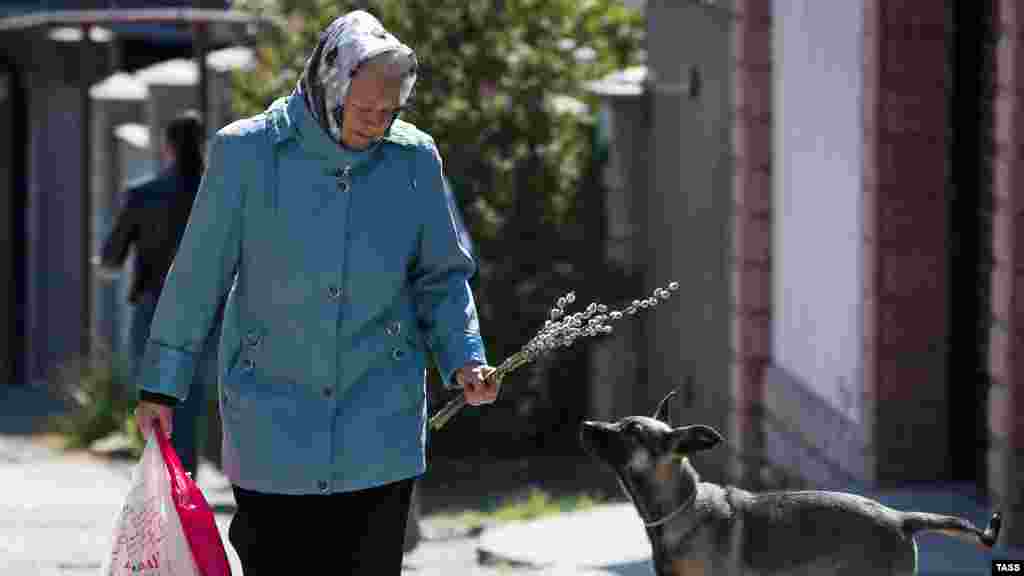 Женщина с веточками вербы на одной из улиц города