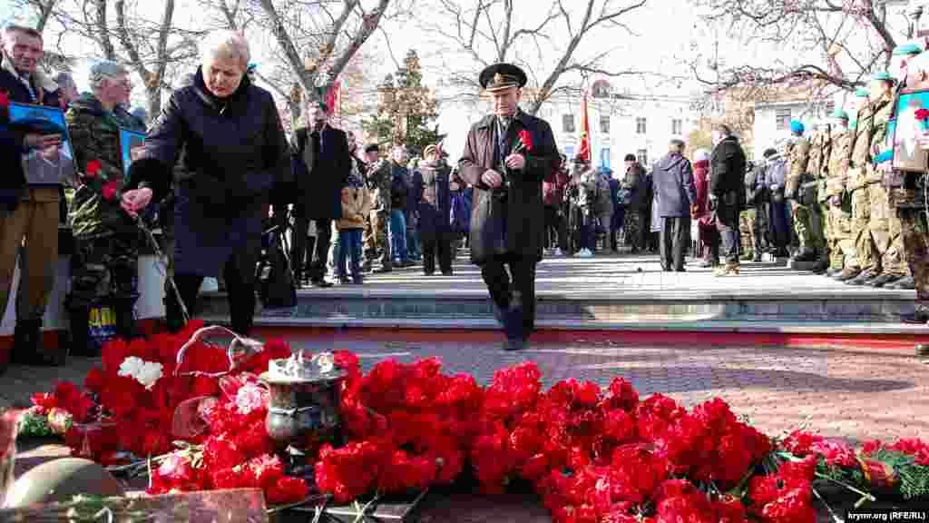 Женщина и офицер в отставке несут цветы к мемориалу советским воинам из Севастополя, погибшим в Афганистане